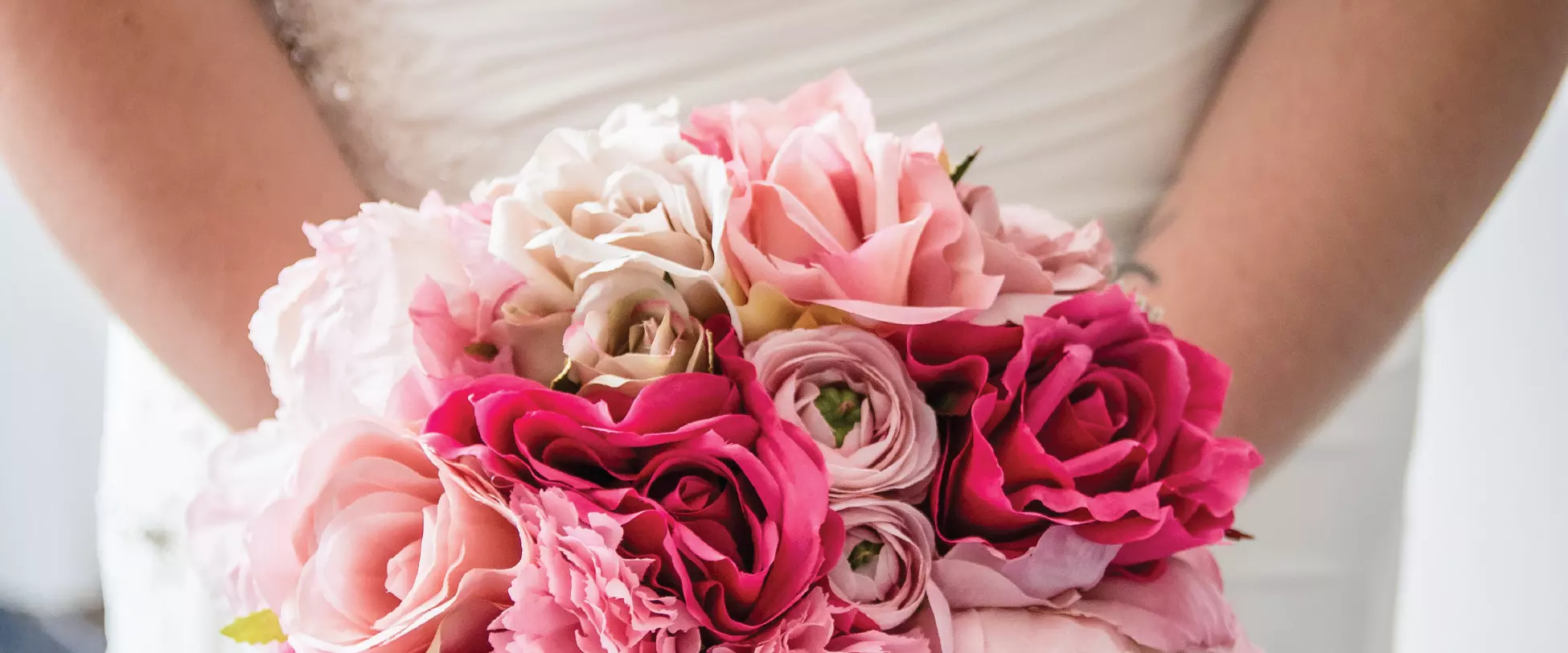 A bride holding a bouquet of hot pink, light pink, and white flowers..